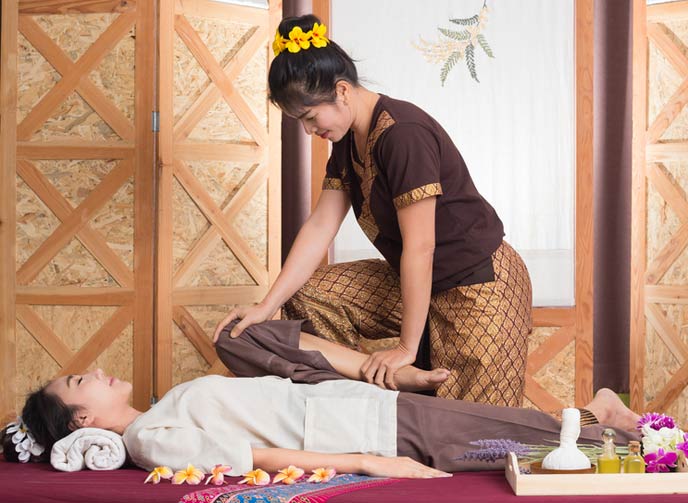 A professional Thai therapist providing Thai stretching massage on the legs of a lady