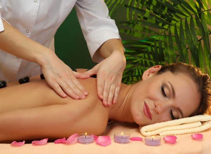 A woman getting a relaxing aromatherapy back massage with candles and flowers around
