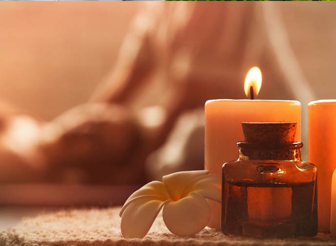 A young woman getting a head massage in a spa with warm ambiance and aromatic candles