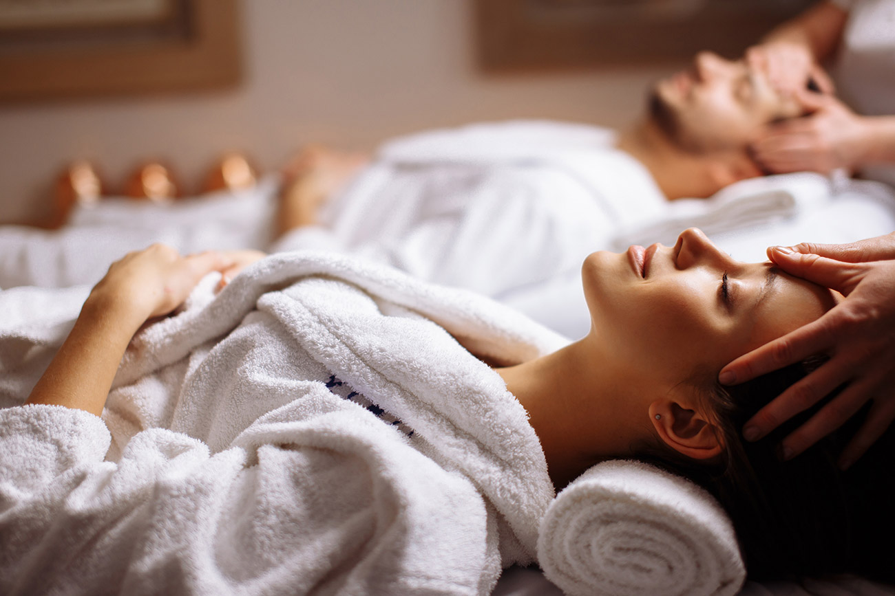 Happy young beautiful couple enjoying head massage spa