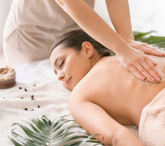 A lady getting an exfoliating full body scrub at a spa in a relaxed ambiance by a professional and skilled masseuse