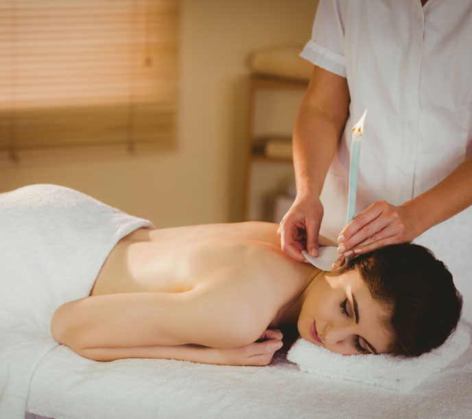 A lady getting a ear candling therapy and ear spa at a professional spa set up