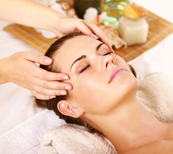 A lady getting a warm face and head massage in a spa