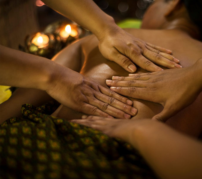 A lady getting a super relaxing four hand massage by two professional Thai therapists in a Thai massage centre